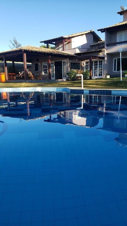 Fachada da pousada em dois andares refletida na piscina