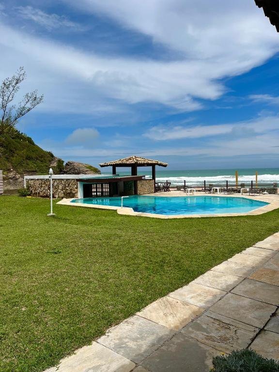 Gramado, piscina e quiosque com o mar ao fundo