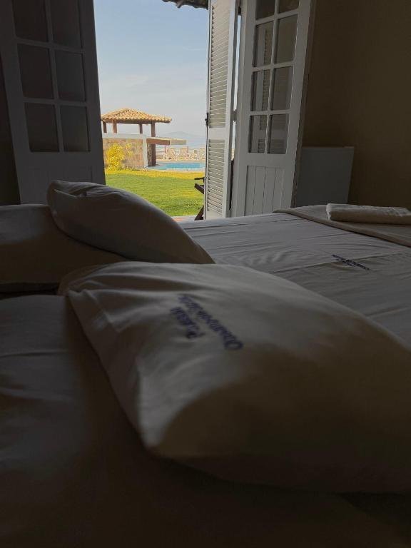 Vista da cama para a piscina e o mar pela porta da suíte